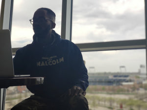 Gentleman wearing From Omaha Like Malcolm hooded sweatshirt while sitting on a mac in front fo T.D. Ameritrade Park.